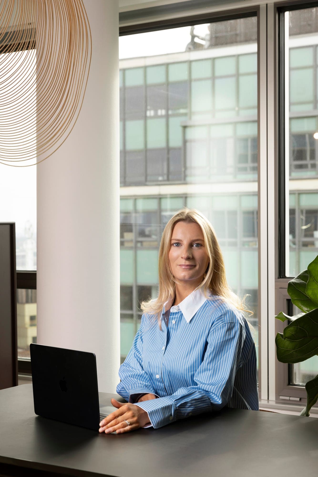 An equity specialist working at a laptop by an office window