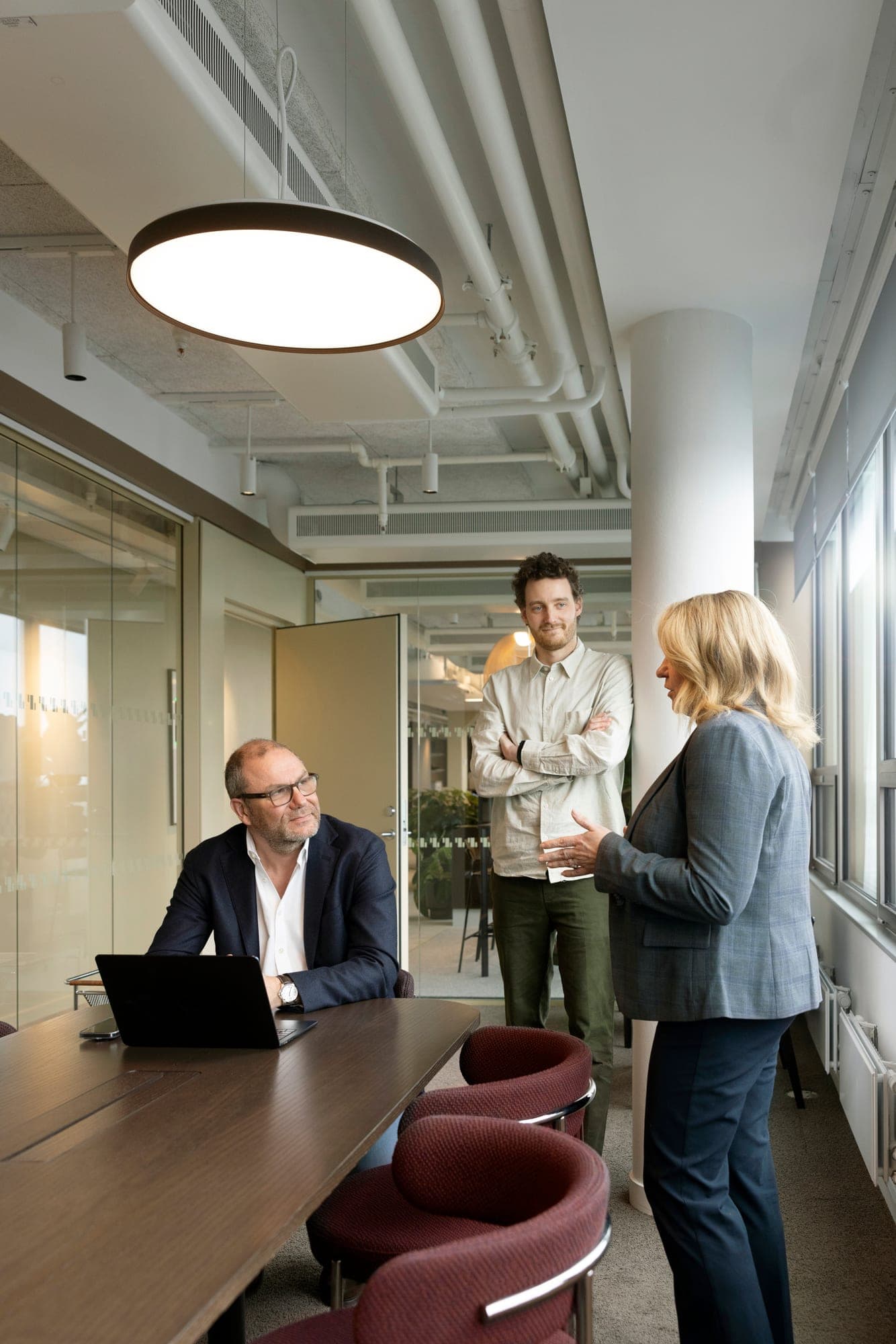 An equity specialist at a laptop while colleagues talk nearby